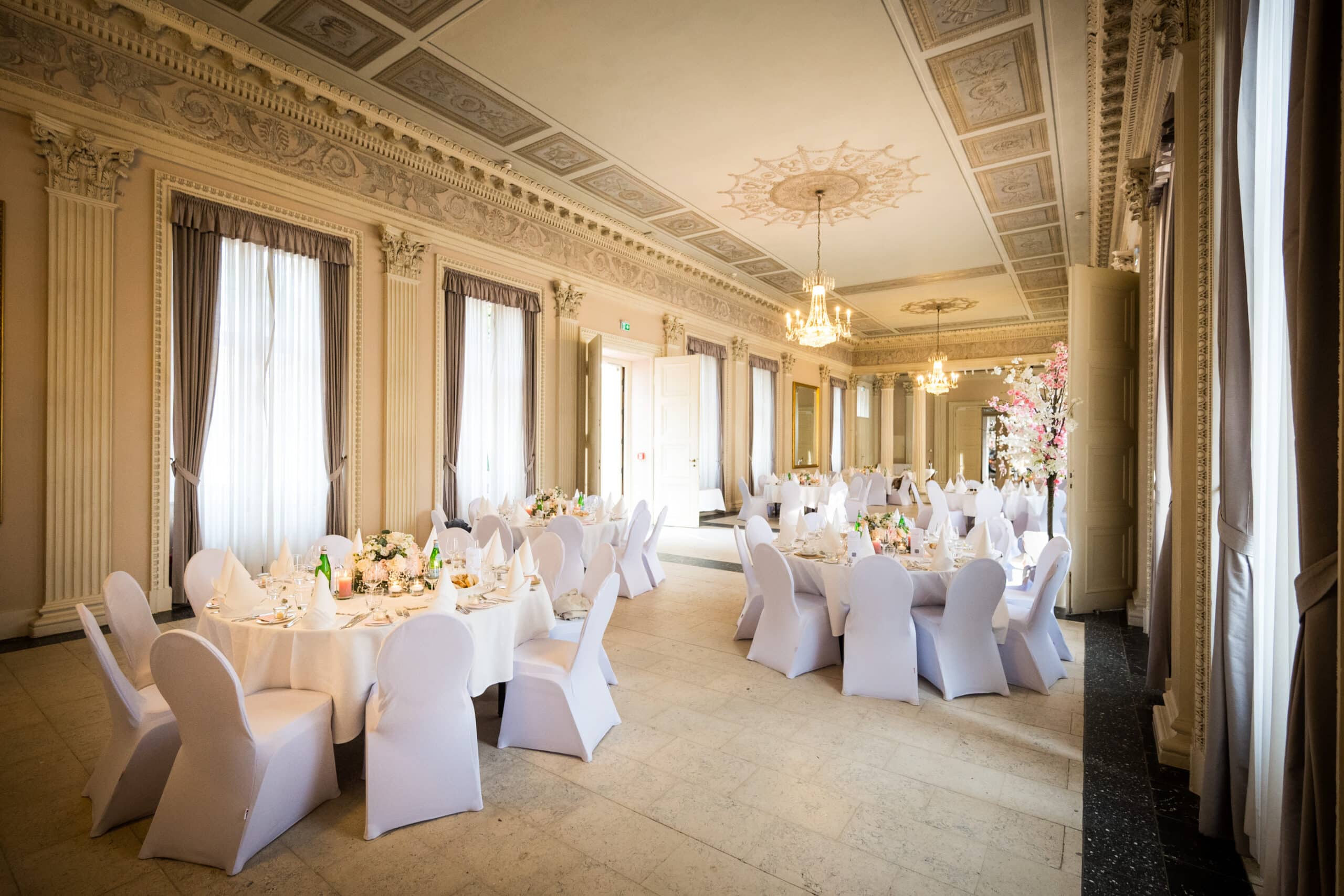 Blick in den Weissen Saal auf Schloss Philippsruhe mit gedeckten Hochzeitstischen