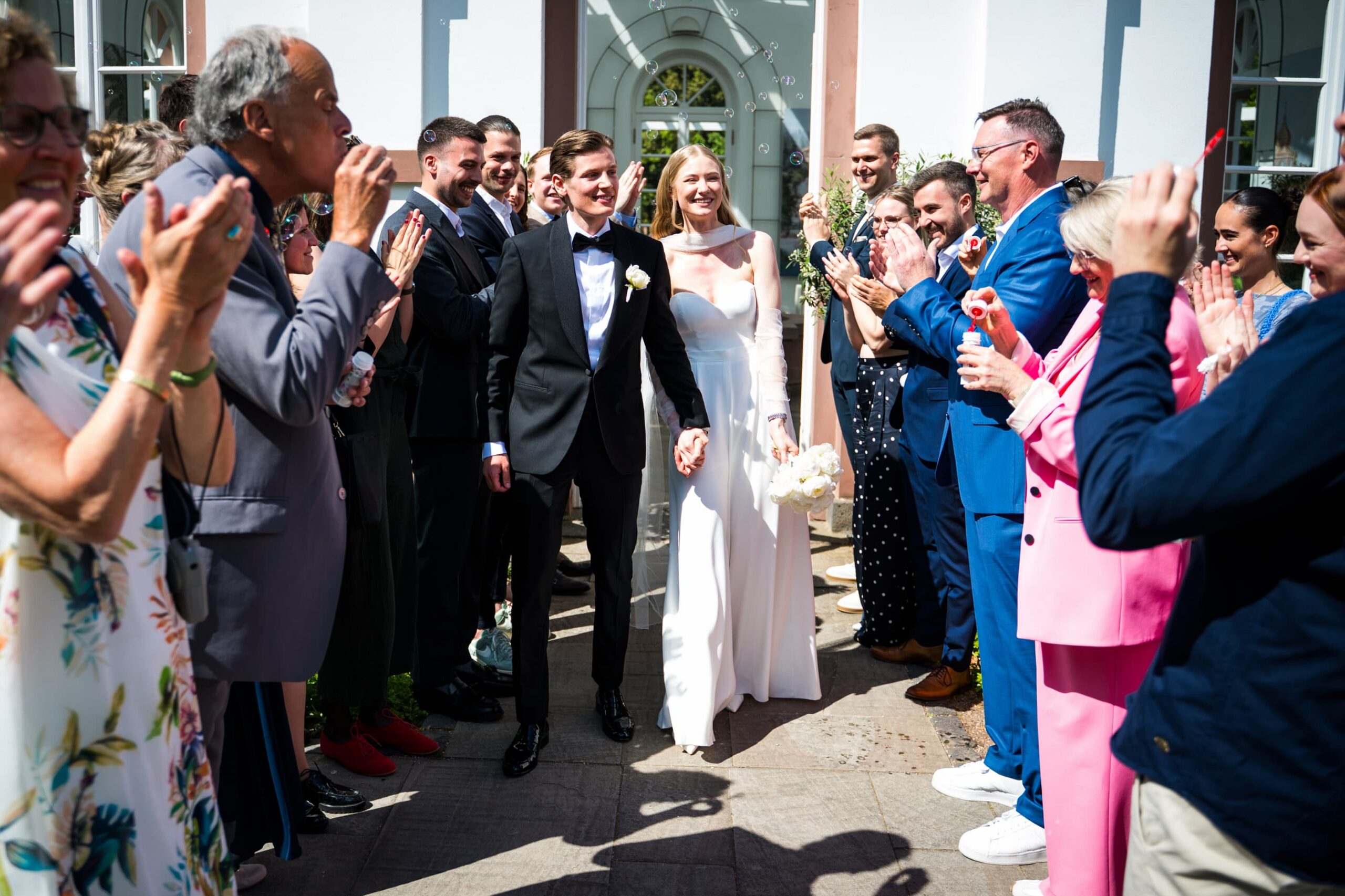 Brautpaar zieht nach der Trauung aus dem Haus Rosenbrunn aus durch ein Spalier - Hochzeitsfotograf Tobias Schnurr