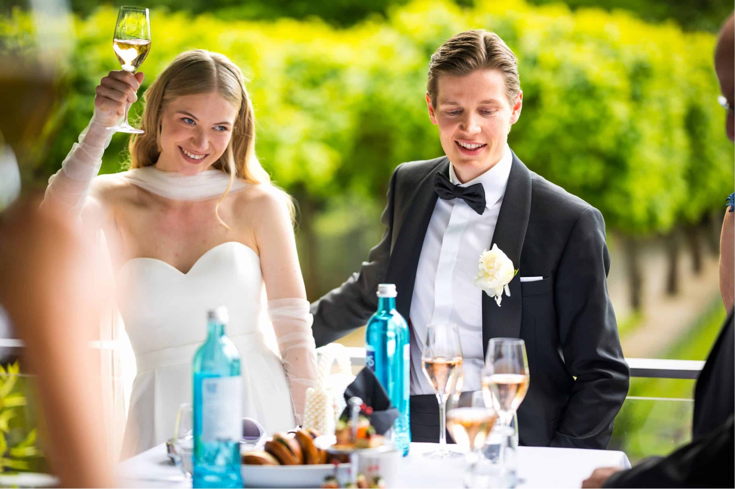 Hochzeitsgäste stoßen mit Sektglas in der Hand an